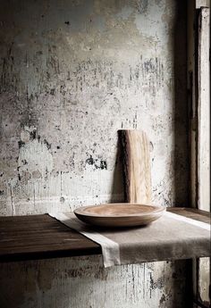 a wooden plate sitting on top of a table next to a wall with peeling paint