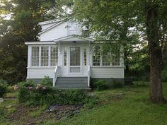 a small white house sitting next to a tree