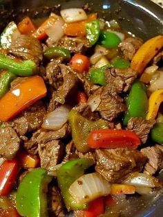 beef and peppers stir fry in a wok on the stove top, ready to be eaten