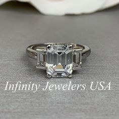 an emerald cut diamond ring with three baguetts on the side and two sides