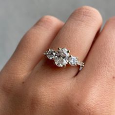 a woman's hand holding an engagement ring with three stones