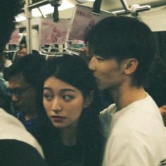 two people standing next to each other on a subway train, looking at something in the distance