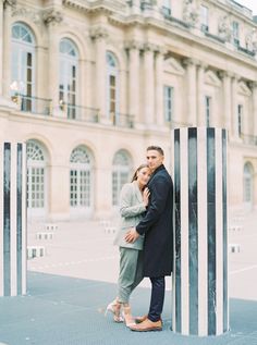 a man and woman standing next to each other in front of a building with columns