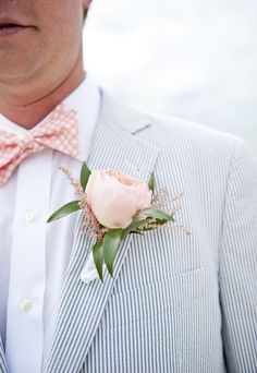 a man in a suit and bow tie with a flower on his lapel pin