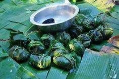 there is a bowl on top of some leafy plants with leaves around it and a metal bowl in the middle