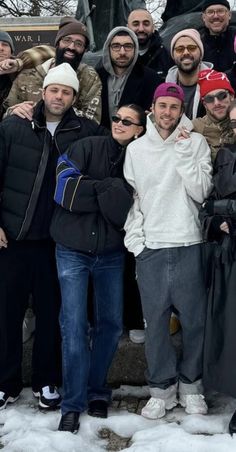 a group of people standing next to each other in front of a statue on top of snow covered ground