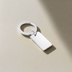 a metal keychain with a blank tag attached to it on a white surface