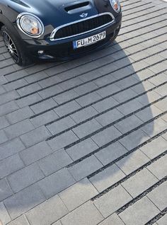 a small black car parked on top of a brick road