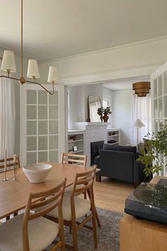 a dining room table with chairs and a bowl on top of it in front of a couch