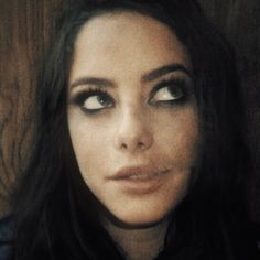 a woman with long hair and blue eyes looks at the camera while wearing a black shirt