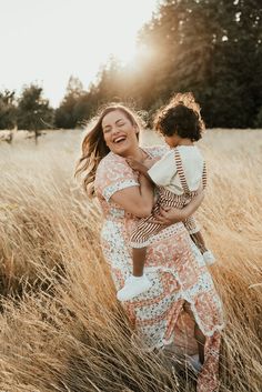 a woman holding a small child in a field