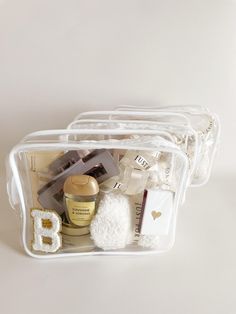 three clear plastic containers filled with cosmetics and personal care items on top of a white surface