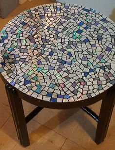 a small table with a mosaic design on it's top sitting on the floor