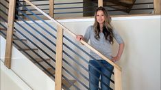 a beautiful young woman standing next to a banister in front of a stair case