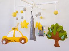 three mobiles hanging from the ceiling with toys in front of them, including a taxi and a tree