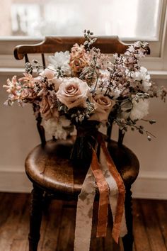 a bouquet of flowers sitting on top of a wooden chair in front of a window