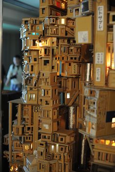 a tall wooden tower with lots of boxes on it's sides and people in the background