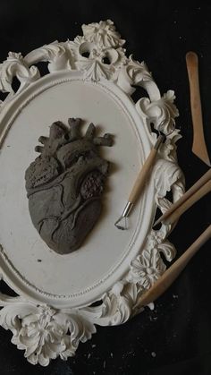 a white plate with a heart shaped cookie on it and two wooden utensils