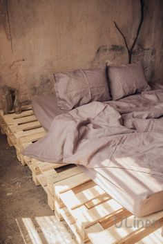 a bed made out of wooden pallets with sheets and pillows on top of it