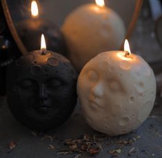 two candles with faces on them sitting next to each other in front of a mirror