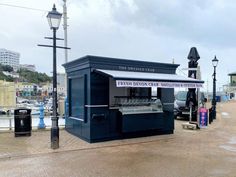 an outdoor kiosk is on the side of the road near some parked cars