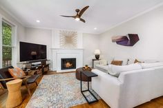 a living room filled with furniture and a flat screen tv mounted on a wall above a fire place