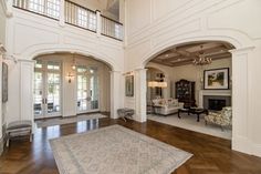 a large living room with wood floors and white walls, along with two chandeliers hanging from the ceiling