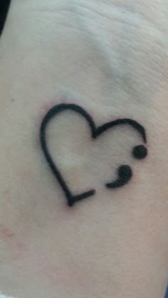 a small black heart tattoo on the wrist