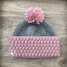 a crocheted beanie with a pink pom - pom on top