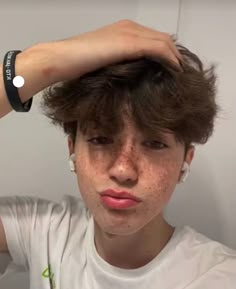 a young man with freckles on his hair is looking at the camera while wearing a white t - shirt