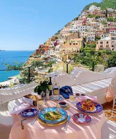 the table is set for two on the balcony overlooking the ocean and town in the background