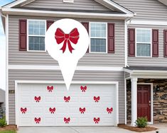 a large white heart with red bows on the side of a house in front of a driveway