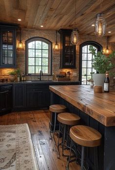 a large kitchen with wooden floors and black cabinetry, along with stools that match the hardwood flooring