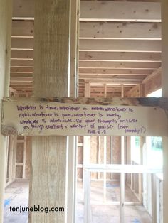 a sign that is hanging on the side of a wooden pole in a house under construction