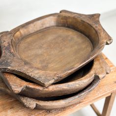 an old wooden tray sitting on top of a wooden table next to another wood plate