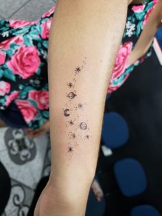 a woman's arm with stars and planets tattooed on the left side of her arm