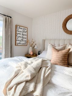 a bed with white sheets and pillows on top of it next to a large window