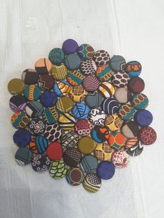 a pile of colorful buttons sitting on top of a white cloth covered table next to each other