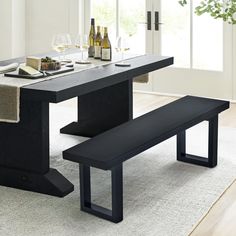 a dining table with two benches and wine bottles on the table in front of it