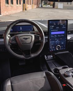 the interior of a car with an electronic display and steering wheel control, along with other accessories