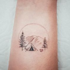 a person with a tattoo on their arm that has a tent and trees in the background