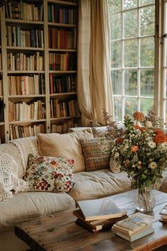 a living room filled with lots of books and flowers on top of a wooden table