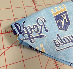 a blue kansas royals necktie laying on top of a cutting board next to a ruler