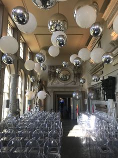 a room filled with lots of clear chairs and shiny balls hanging from the ceiling above them