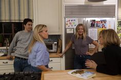 three people in a kitchen talking to each other