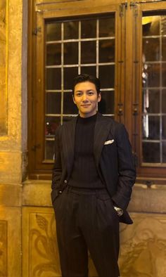 a man standing in front of a window wearing a suit