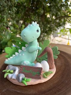 a cake shaped like a dinosaur sitting on top of a wooden table next to a tree