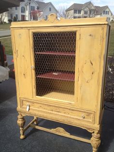 an old yellow cabinet with chicken wire doors