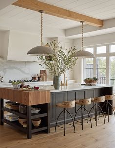 a large kitchen island with stools in front of it and two lights hanging from the ceiling