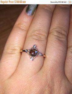 a woman's hand with a ring on it that has a brown and white diamond in the middle